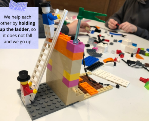 Scène Lego représentant une figurine tenant l'échelle pour une autre, afin de symboliser leur soutien mutuel.